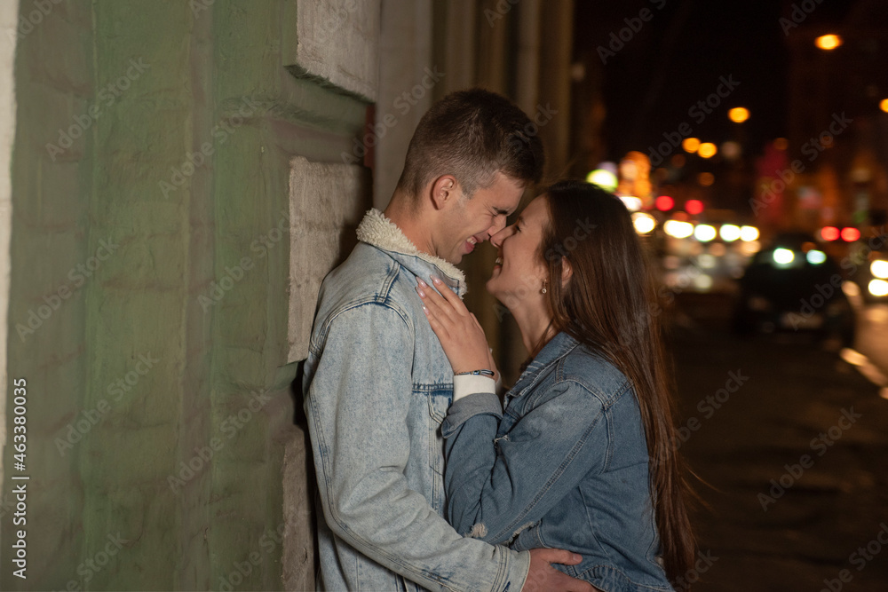 Portrait of laughing young couple and kissing on night city background. Romantic date. young couple in love.