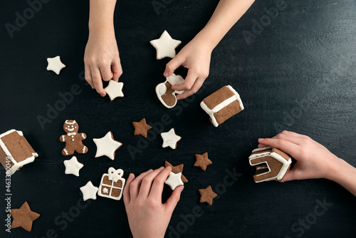 Gingerbread homemade cookies in children's hands . New Year sweets. Black background