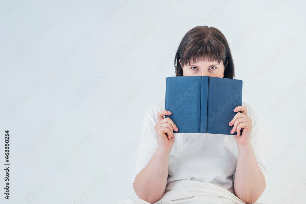 Portrait of young dark-haired woman with book in her hands on white background. Concept of education. Portrait of young dark-haired woman with book in her hands on white background. Concept of education.