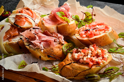 Antipasto. Italian food. Bruschetta with prosciutto, cheese and salmon on a wooden board. Top view. Rustic style.