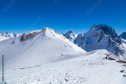Caucasus Mountains, Panoramic view of the ski slope with the mountains Belalakaya, Sofrudzhu and Sulakhat on the horizon in winter day. Dombai ski resort, Western Caucasus, Karachai-Cherkess, Russia. © evgenii