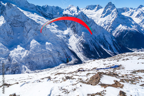 Paragliding in the mountains, People paragliding tandem above mountain in winter in Dombay ski resort. Concept of active lifestyle and extreme sport adventure.