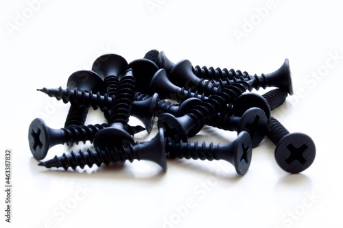 Pile of black screws laying on white underground
