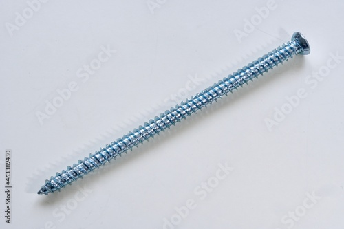 Single long silver screw for windows or frames on white background