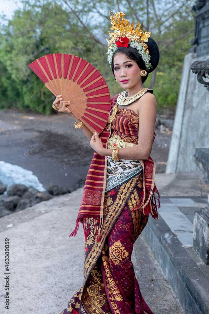 Balinese Woman In Traditional Costume And Hand Fan Indonesian Girl Hindu Temple Background