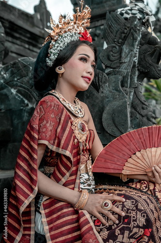 Balinese woman in traditional costume and hand fan, indonesian girl, hindu temple background, Bali.