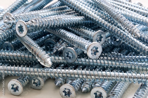 Closeup of pile of long silver screws for windows or frames on white background