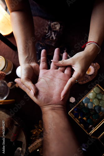 A woman performs a hand reading at her witch altar with various objects such as tarot cards, crystals and candles