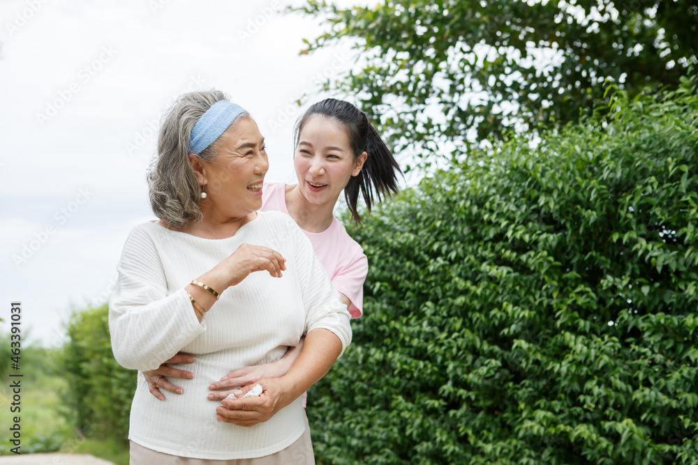 asian adult daughter hug her senior mother in backyard garden  at home . young woman embrace old mom  to take care in park outdoors.