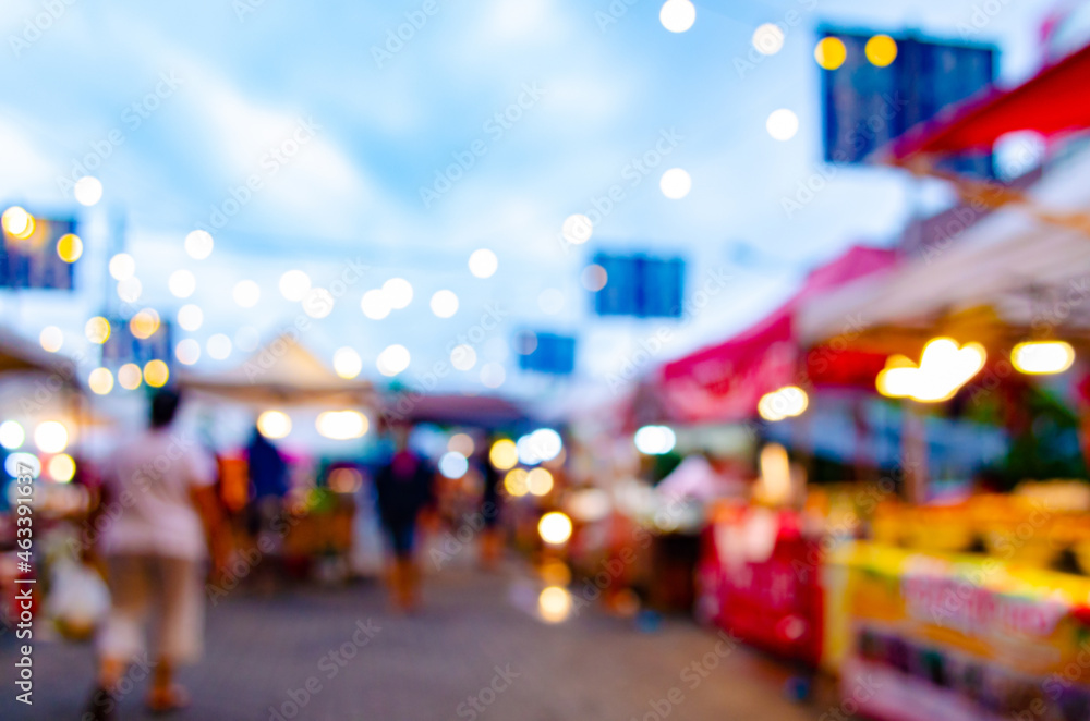 An abstract blur of an evening night market where people start shopping happily during COVID