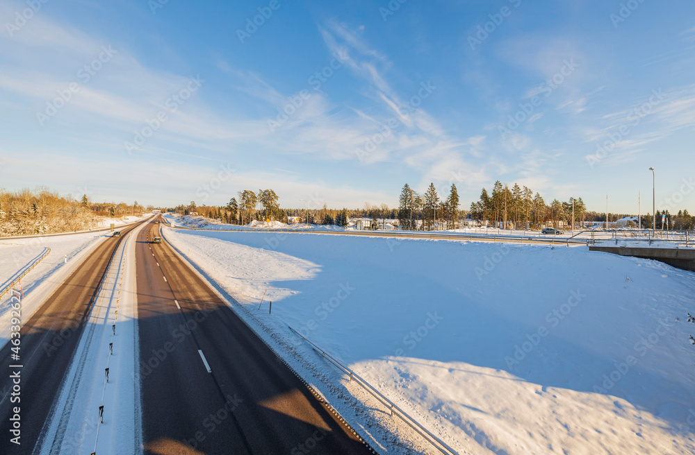  View of with a bridge on a snowy highway on a background of blue sky. Sweden. 
