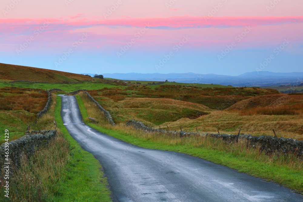 Sunrise image of a Lonely single track road at Stainmore near Kirkby Stephen, Cumbria, England, UK.