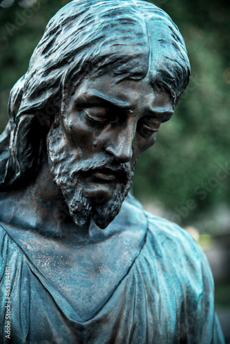 A fragment of ancient figure of the sad Jesus Christ in the old cemetery as a symbol of love and salvation of mankind after death in the kingdom of eternity.