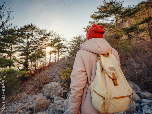 man with backpack and red hat hiking in the sunset mountains stands on rocky hiking trail or path. Cold weather. Winter hike. Outdoor vibes and adventures wanderlust