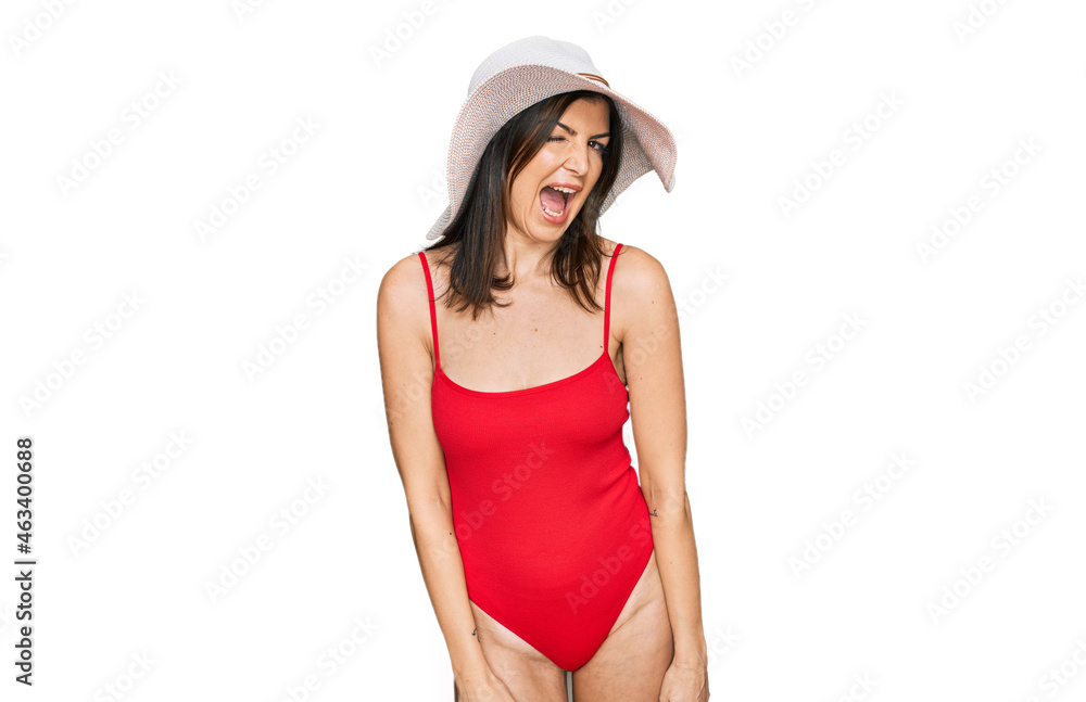 Beautiful brunette woman wearing swimsuit and summer hat winking looking at the camera with sexy expression, cheerful and happy face. Beautiful brunette woman wearing swimsuit and summer hat winking looking at the camera with sexy expression, cheerful and happy face.