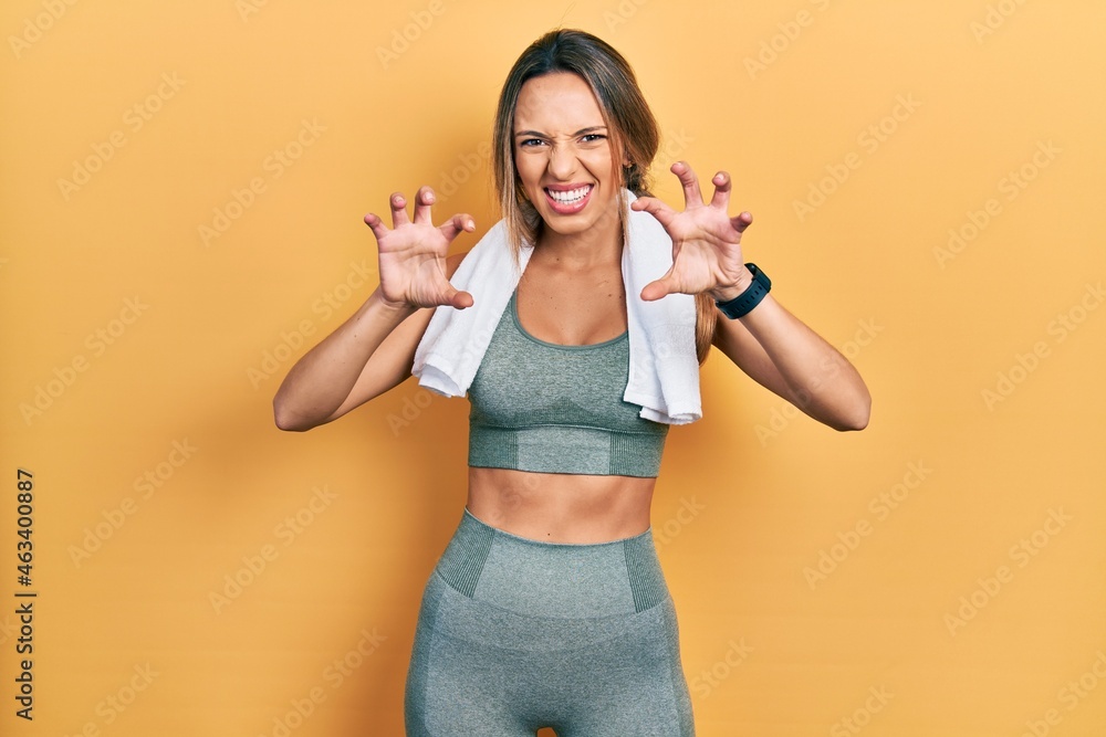 Beautiful hispanic woman wearing sportswear and towel smiling funny doing claw gesture as cat, aggressive and sexy expression Beautiful hispanic woman wearing sportswear and towel smiling funny doing claw gesture as cat, aggressive and sexy expression