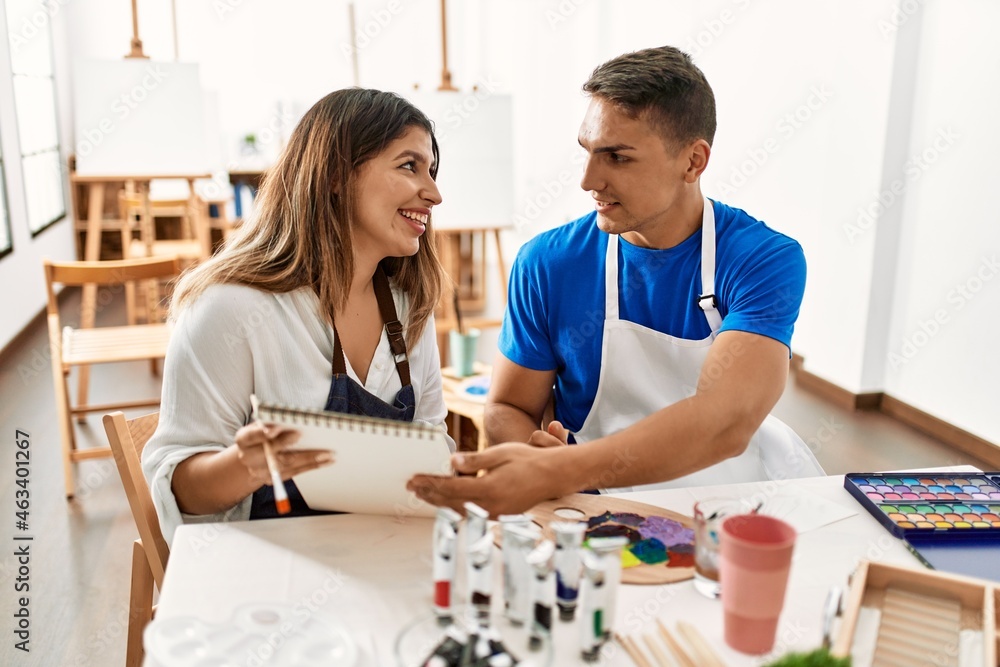 Two students smiling happy painting sitting on the table at art school. Two students smiling happy painting sitting on the table at art school.