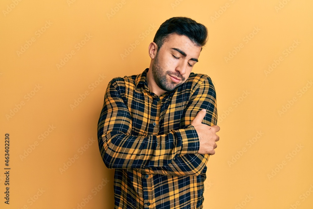Young hispanic man wearing casual clothes hugging oneself happy and positive, smiling confident. self love and self care Young hispanic man wearing casual clothes hugging oneself happy and positive, smiling confident. self love and self care