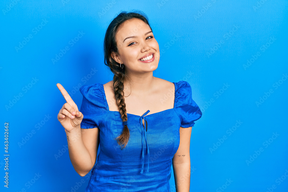 Young hispanic girl wearing casual clothes showing and pointing up with finger number one while smiling confident and happy. Young hispanic girl wearing casual clothes showing and pointing up with finger number one while smiling confident and happy.