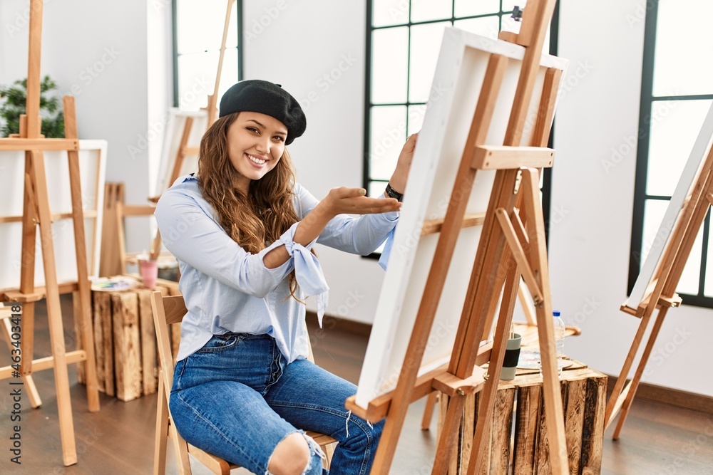 Young hispanic artist woman painting on canvas at art studio pointing aside with hands open palms showing copy space, presenting advertisement smiling excited happy Young hispanic artist woman painting on canvas at art studio pointing aside with hands open palms showing copy space, presenting advertisement smiling excited happy