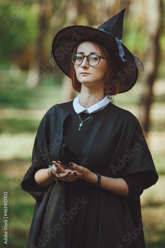 Obraz na płótnie Halloween witch. Portrait of a girl in a hat and witch costume and with a black raven in the forest. Ready for the holiday wallet or life w salonie