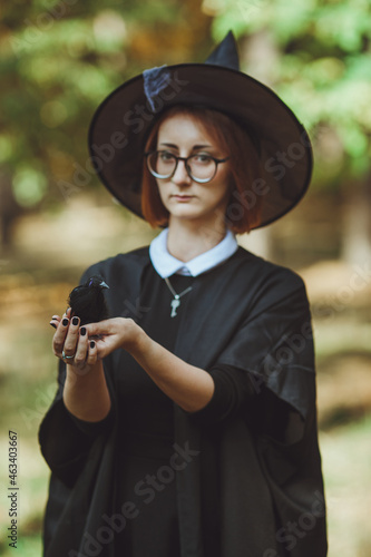 Obraz na płótnie Halloween witch. Portrait of a girl in a hat and witch costume and with a black raven in the forest. Ready for the holiday wallet or life w salonie