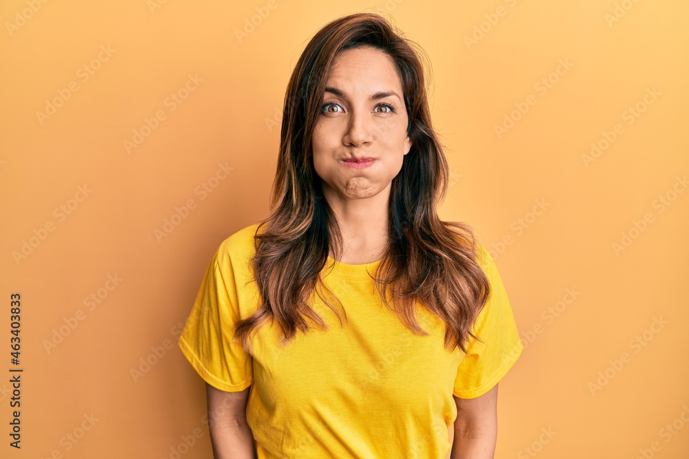 Young latin woman wearing casual clothes puffing cheeks with funny face. mouth inflated with air, crazy expression. Young latin woman wearing casual clothes puffing cheeks with funny face. mouth inflated with air, crazy expression.
