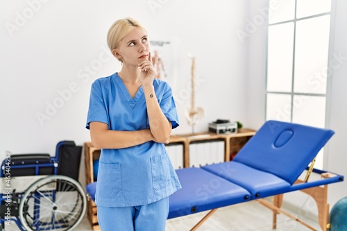 Beautiful caucasian physiotherapist woman working at pain recovery clinic with hand on chin thinking about question  pensive expression. smiling with thoughtful face. doubt concept.