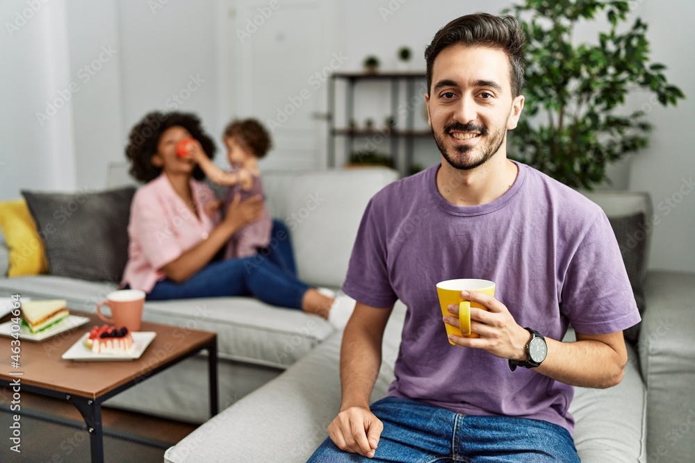 Hispanic father of interracial family drinking a cup coffee with a happy and cool smile on face. lucky person. Hispanic father of interracial family drinking a cup coffee with a happy and cool smile on face. lucky person.
