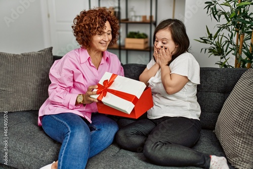 Mature mother and down syndrome daughter at home giving a surprise gift to the other