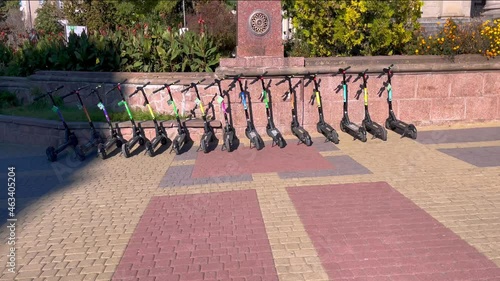 Electric scooters stand near the fence in the city center. Environmentally friendly mode of transport in the city. Rental of electric scooters on the streets of the city.