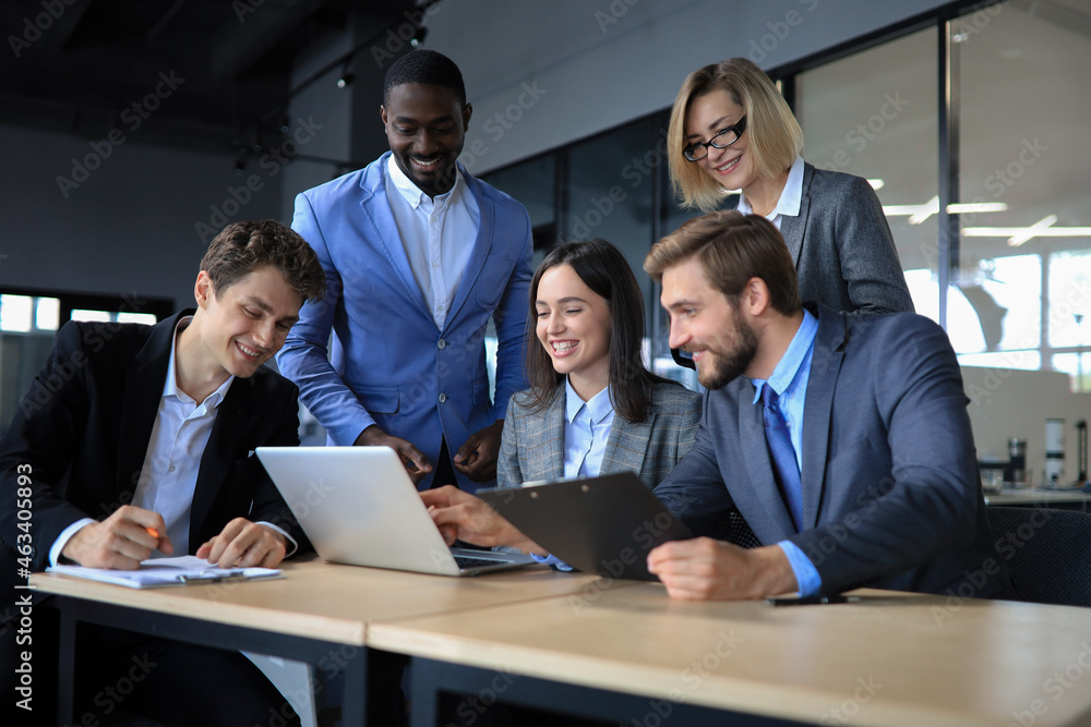 Happy business people laugh near laptop in the office. Successful team coworkers joke and have fun together at work.