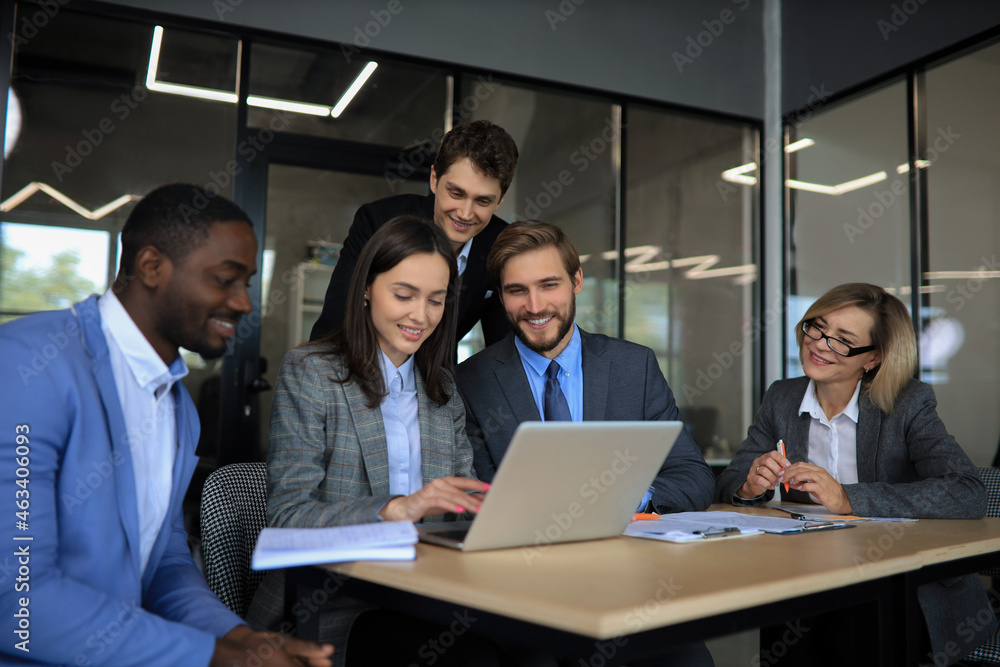 Group of happy diverse male and female business people in formal gathered around laptop computer in bright office. Group of happy diverse male and female business people in formal gathered around laptop computer in bright office.