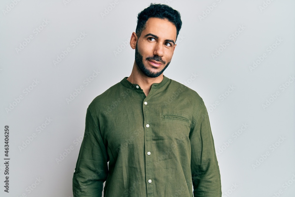 Obraz premium Young hispanic man wearing casual clothes smiling looking to the side and staring away thinking.