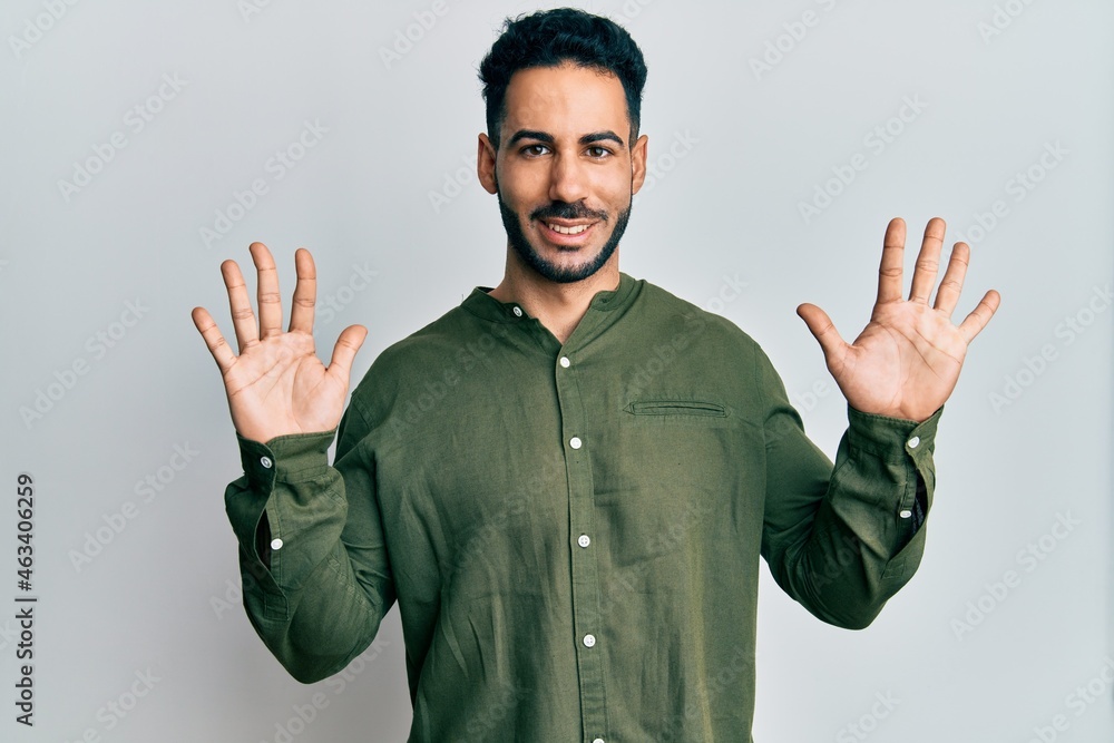 Young hispanic man wearing casual clothes showing and pointing up with fingers number ten while smiling confident and happy. Young hispanic man wearing casual clothes showing and pointing up with fingers number ten while smiling confident and happy.