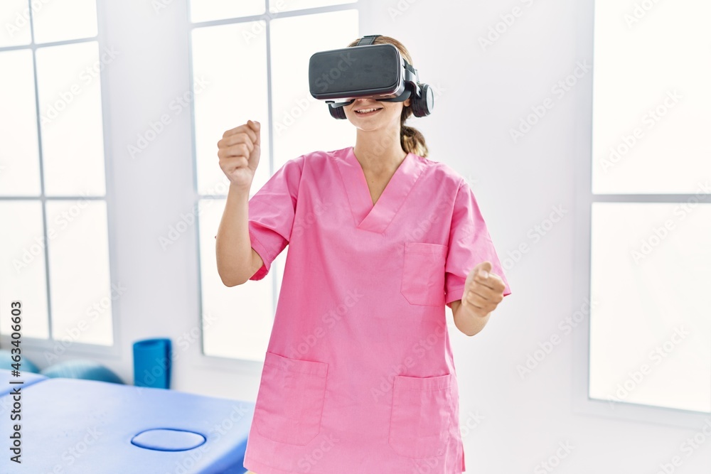 Young caucasian woman wearing physiotherapist uniform using vr glasses at physiotherapy clinic Young caucasian woman wearing physiotherapist uniform using vr glasses at physiotherapy clinic