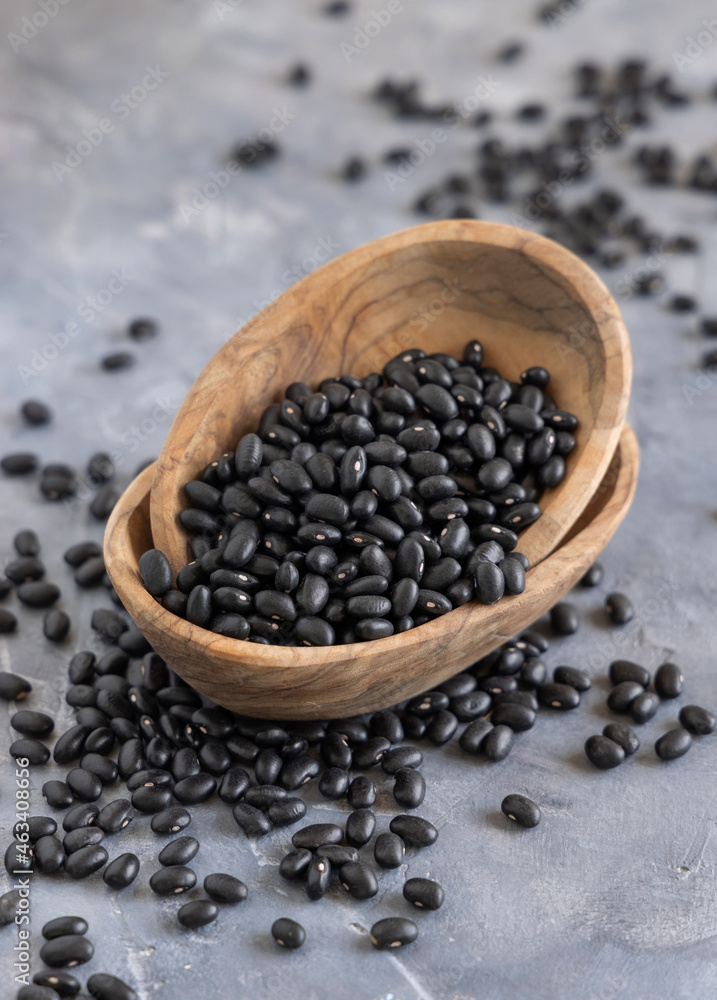 Wooden bowls full of dry black beans on grey table closeup Wooden bowls full of dry black beans on grey table closeup