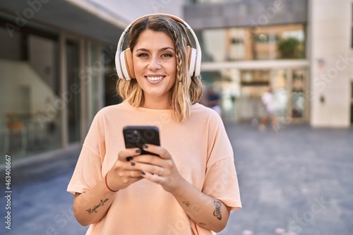 Young hispanic woman smiling confident listening to music at street