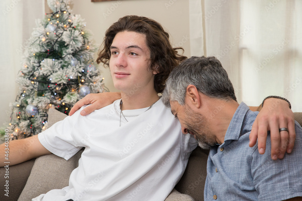 un père de famille fait un câlin à son fils et met la tête sur son épaule le jour de noël, ils sont heureux un père de famille fait un câlin à son fils et met la tête sur son épaule le jour de noël, ils sont heureux