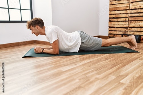 Young caucasian man smiling confident training abs exercise at sport center