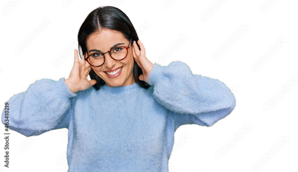 Young hispanic woman wearing casual clothes and glasses covering ears with fingers with annoyed expression for the noise of loud music. deaf concept.