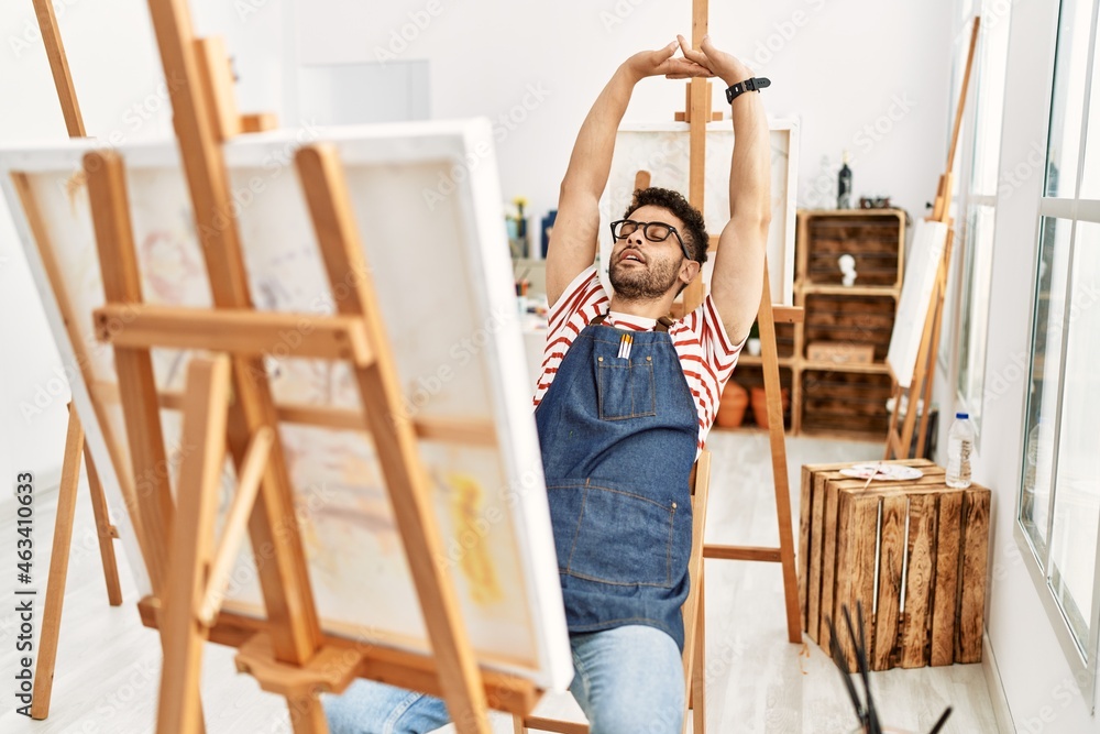 Young arab artist man stretching arms at art studio.