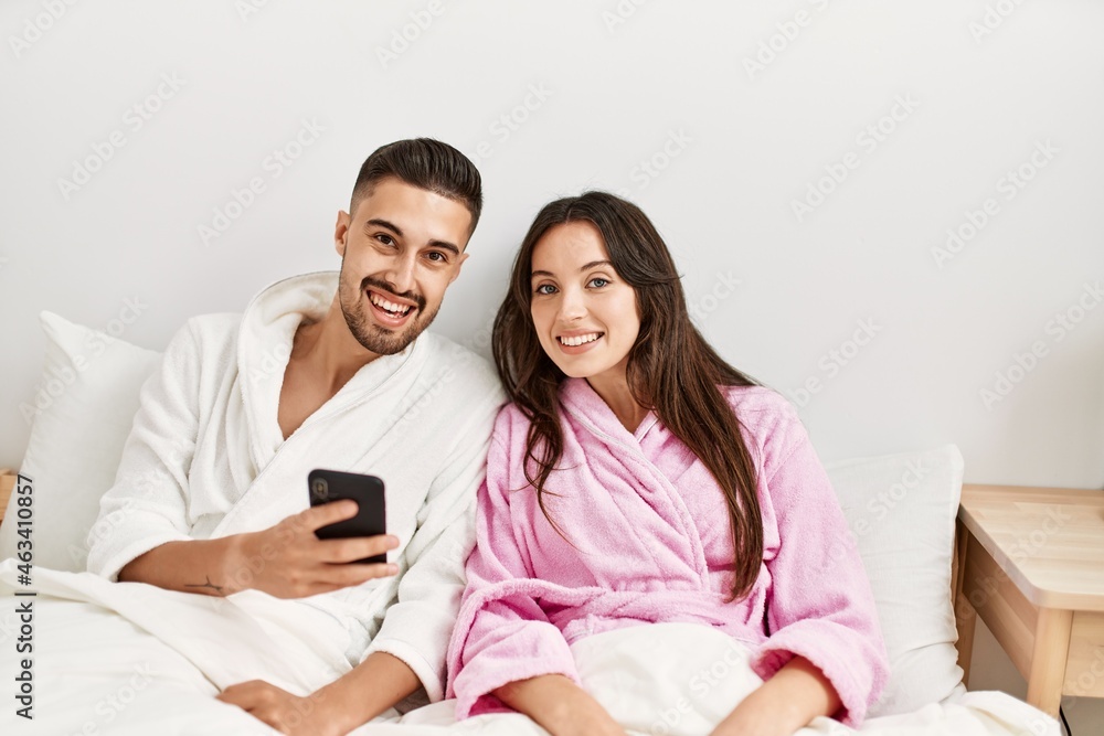 Young hispanic couple using smartphone lying on bed at home. Young hispanic couple using smartphone lying on bed at home.