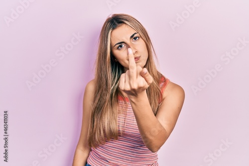 Beautiful hispanic woman wearing casual summer t shirt showing middle finger, impolite and rude fuck off expression