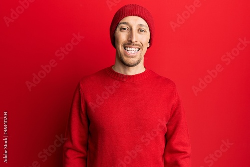 Bald man with beard wearing wool sweater and winter hat with a happy and cool smile on face. lucky person. © Krakenimages.com