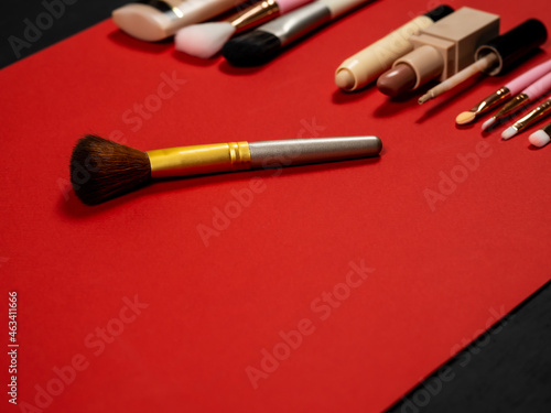 A set of decorative cosmetics. Lipstick, powder and makeup brush, foundation, cosmetic brush, eye concealer. Cosmetic set. Red background.