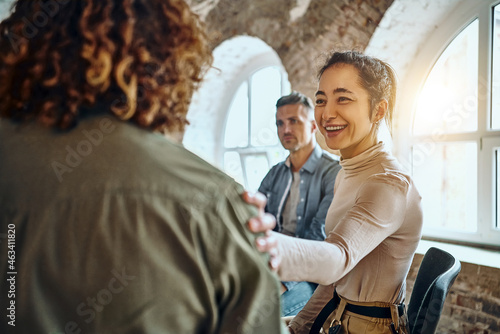 Close-up view of a back of a young man and friends supporting him during group therapy