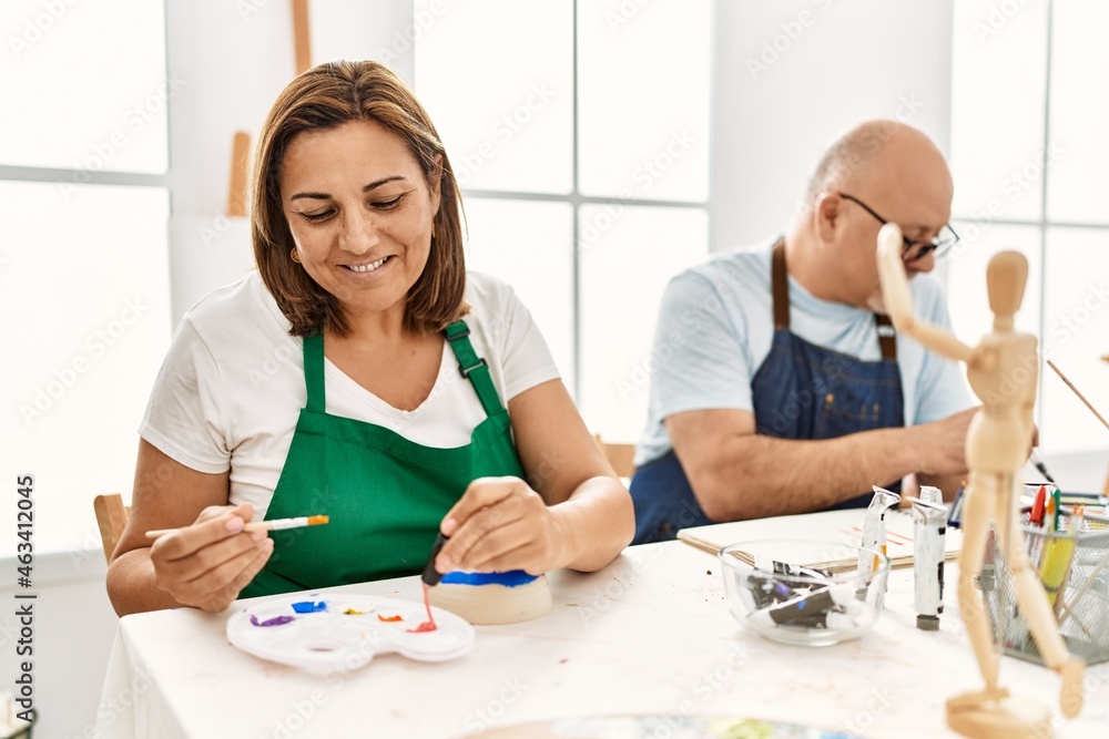 Middle age hispanic painter couple smiling happy painting at art studio. Middle age hispanic painter couple smiling happy painting at art studio.
