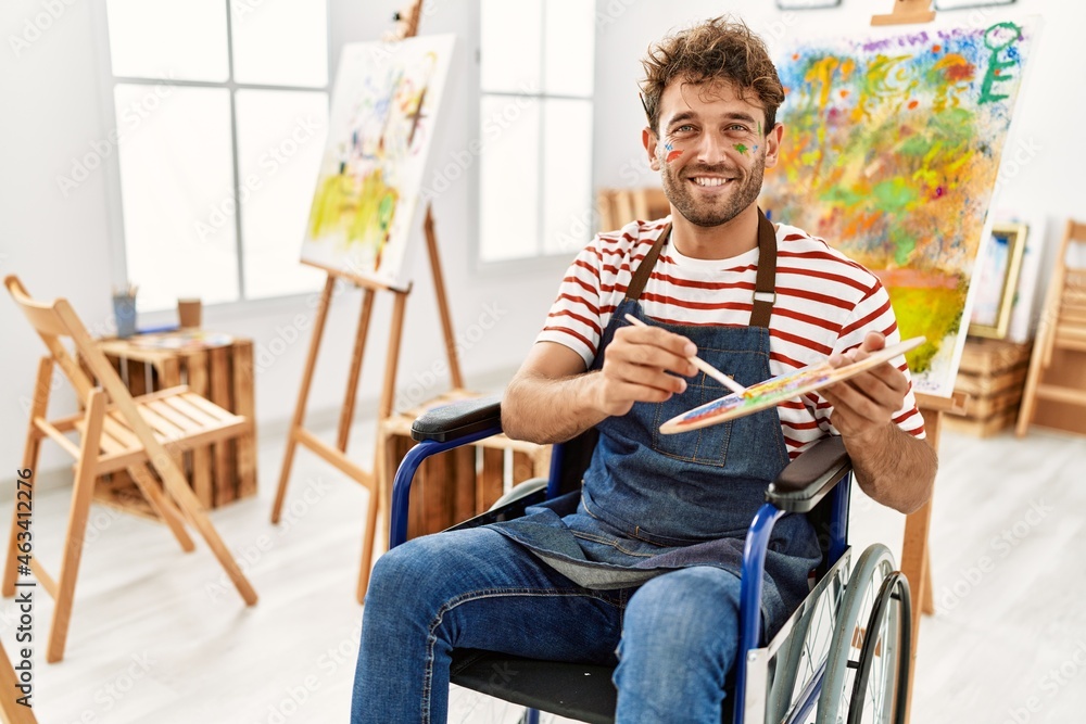 Young hispanic man sitting on wheelchair drawing at art studio