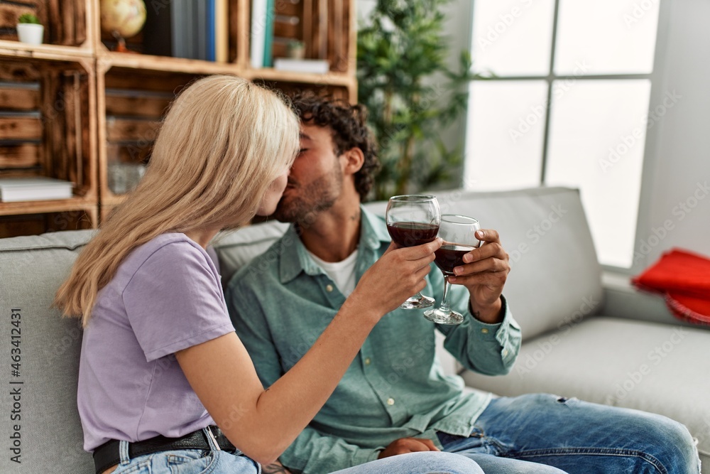 Young couple kissing and toasting with red wine glass at home. Young couple kissing and toasting with red wine glass at home.
